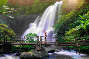 Asian woman wearing Thai dress costume traditional according Thai culture at Pha dok siew waterfall in Chiang Mai Thailand.